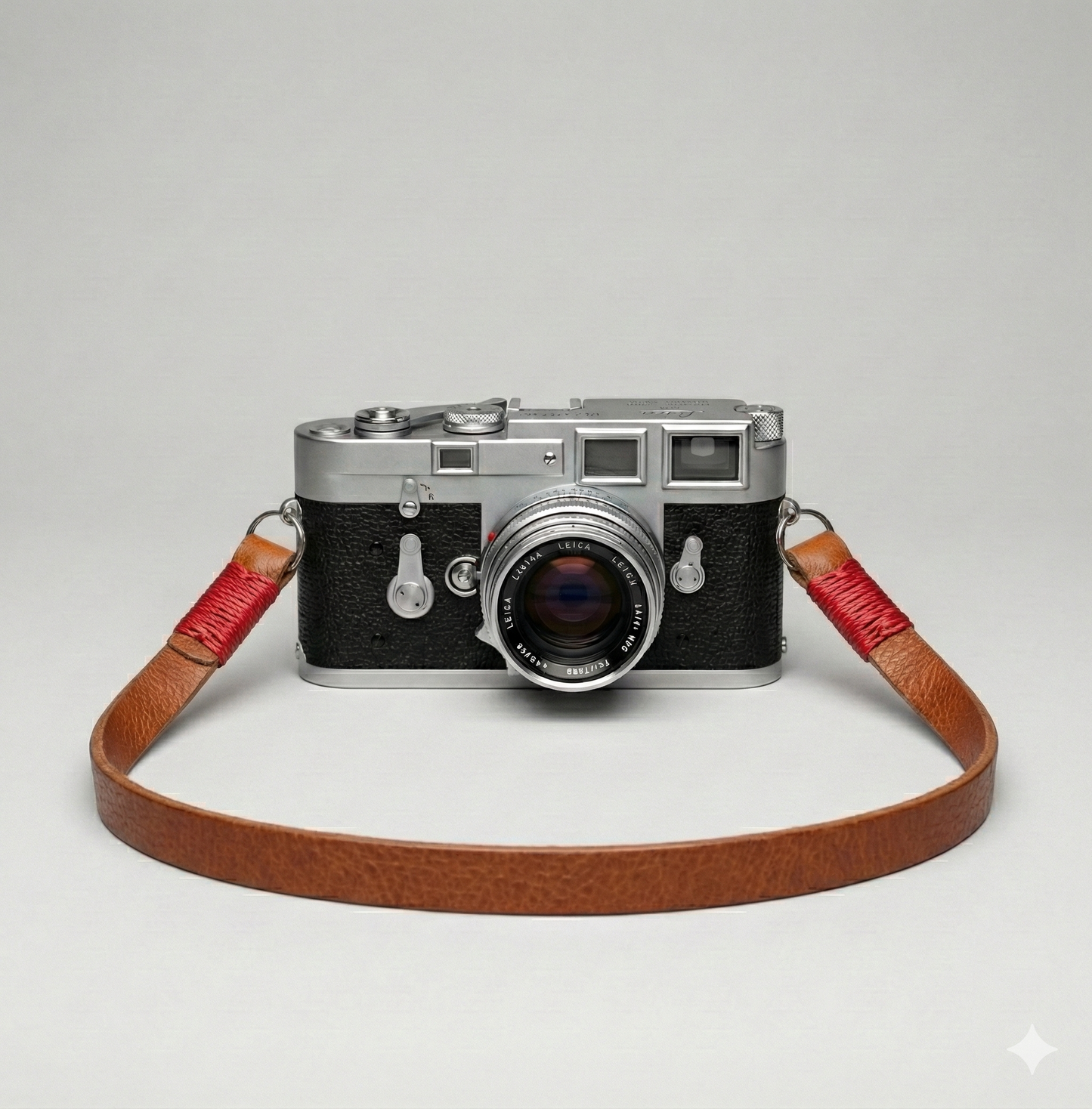 Brown leather camera strap with red wire. 