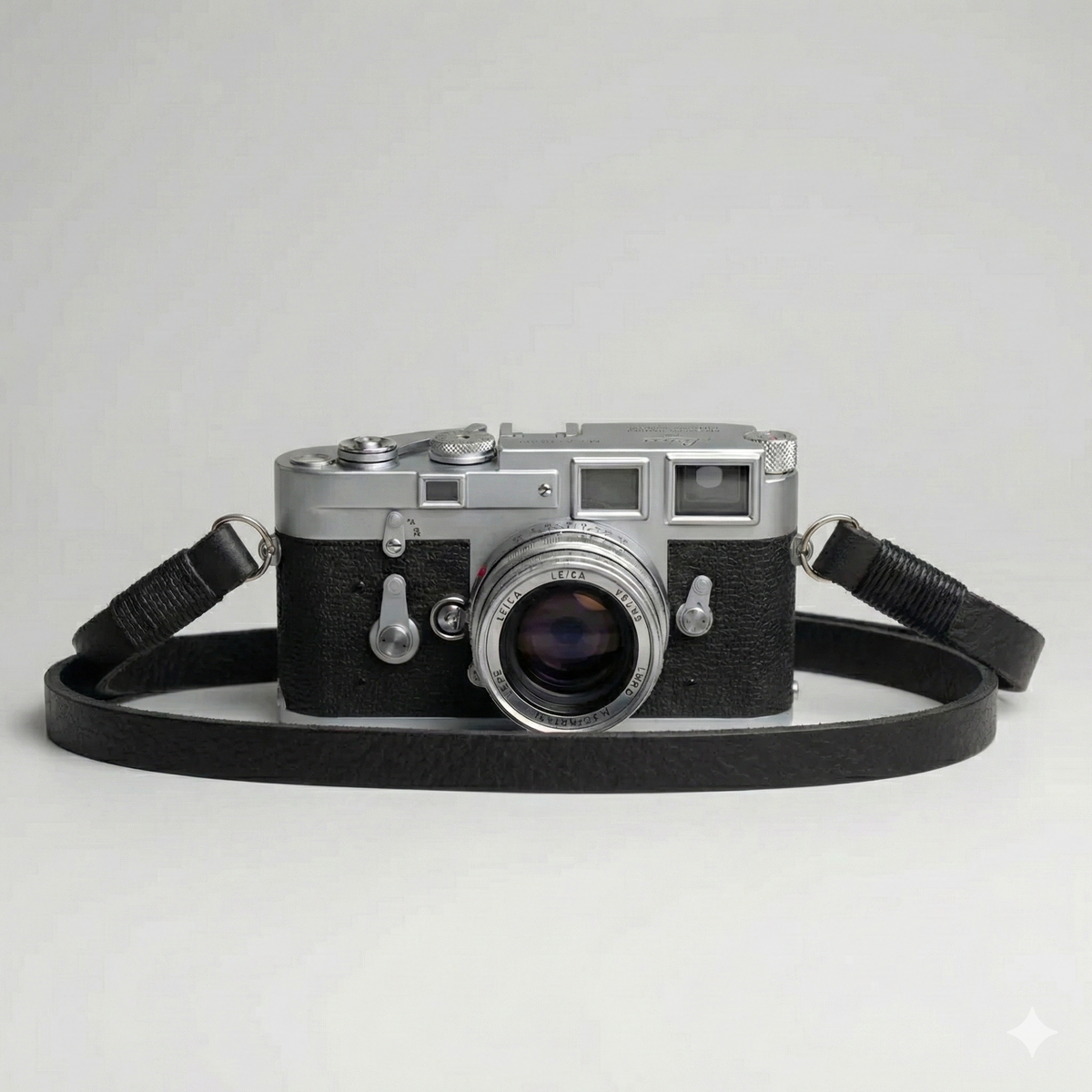 black leather camera strap with black wire. 