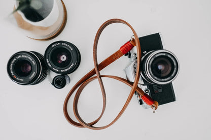 Brown leather camera strap with red wire. 