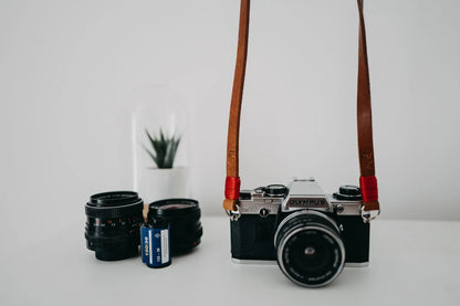 Brown leather camera strap with red wire. 